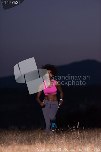 Image of Young African american woman jogging in nature