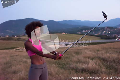 Image of black woman photographing herself in nature