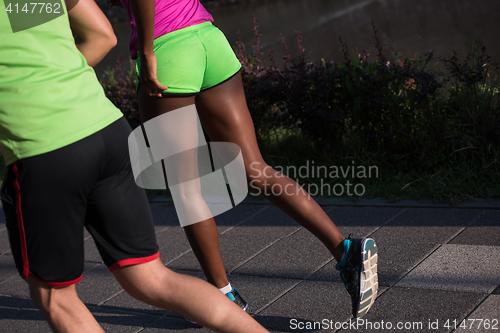 Image of young smiling multiethnic couple jogging in the city