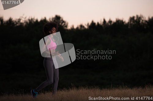 Image of Young African american woman jogging in nature