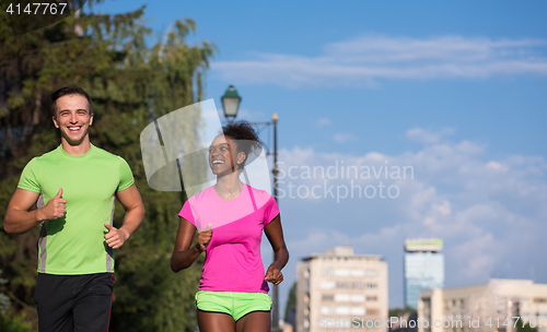 Image of young smiling multiethnic couple jogging in the city