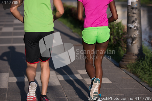 Image of young smiling multiethnic couple jogging in the city