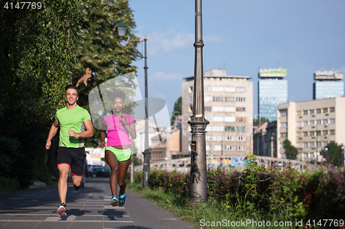 Image of young smiling multiethnic couple jogging in the city