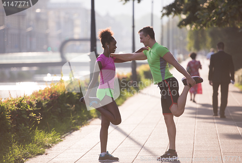 Image of jogging couple warming up and stretching in the city