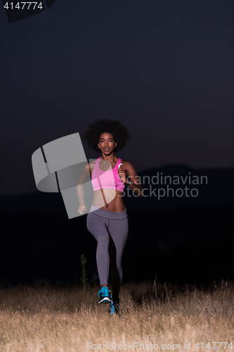 Image of Young African american woman jogging in nature