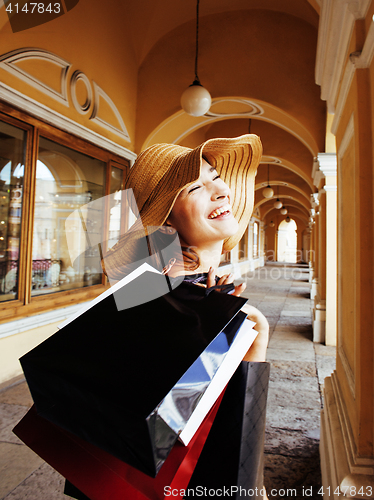 Image of young pretty smiling woman in hat with bags on shopping at store