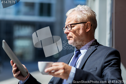 Image of senior businessman with tablet pc drinking coffee