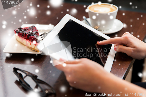 Image of close up of hands with tablet pc, coffee and cake