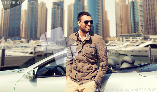 Image of happy man near cabriolet car on city 