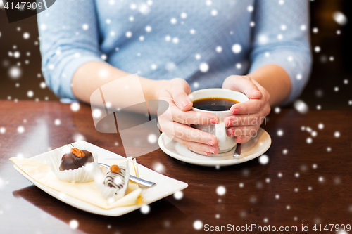 Image of close up of woman holding coffee cup and dessert