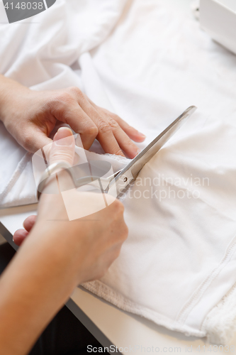 Image of Girl cuts cloth with scissors