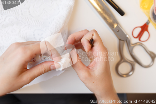 Image of Woman unrips fabric near sewing-machine