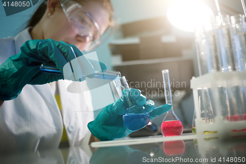 Image of Young laboratory assistant with flasks