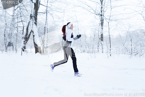 Image of Woman jogging in winter woods