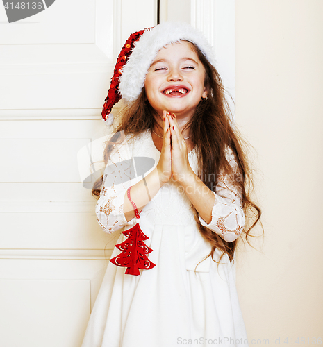 Image of little cute girl in santas red hat waiting for Christmas gifts. 