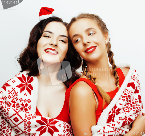 Image of young pretty happy smiling blond and brunette woman girlfriends on christmas in santas red hat and holiday decorated plaid, lifestyle people concept