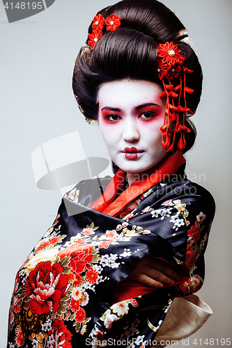 Image of young pretty geisha in black kimono among sakura, asian ethno