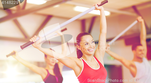 Image of group of smiling people working out with barbells