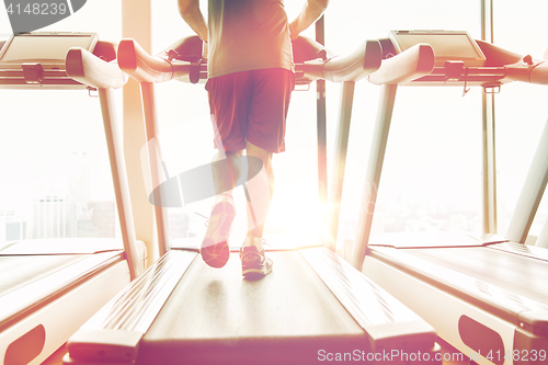 Image of close up of male legs running on treadmill in gym