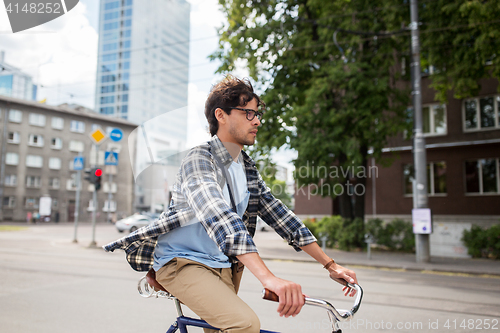 Image of young hipster man with bag riding fixed gear bike