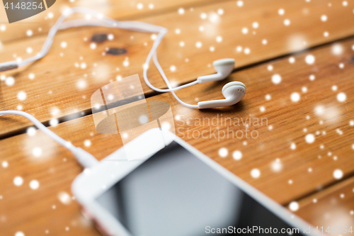 Image of close up of smartphone and earphones on wood