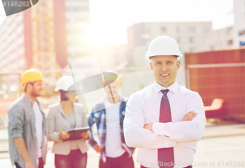 Image of group of smiling builders in hardhats outdoors