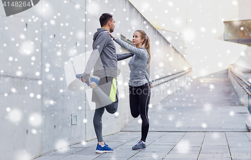 Image of couple of sportsmen stretching leg outdoors