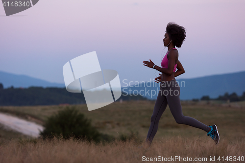 Image of Young African american woman jogging in nature