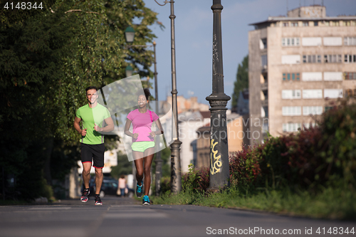 Image of young smiling multiethnic couple jogging in the city