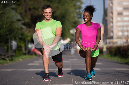 Image of jogging couple warming up and stretching in the city