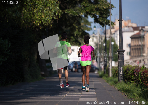 Image of young smiling multiethnic couple jogging in the city