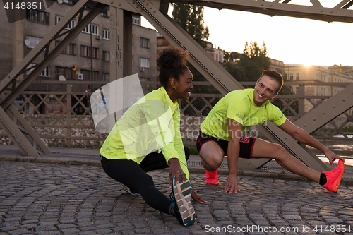 Image of jogging couple warming up and stretching in the city