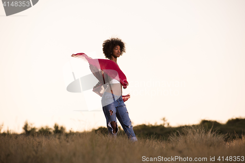 Image of black girl dances outdoors in a meadow