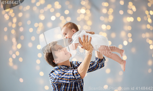 Image of happy young father playing with baby over lights