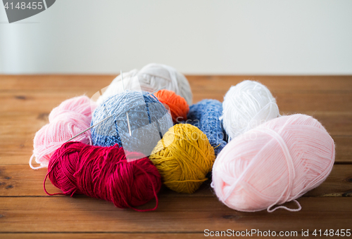 Image of knitting needles and balls of yarn on wood