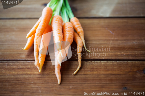 Image of close up of carrot bunch on wooden table