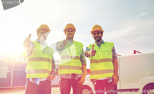 Image of happy male builders in high visible vests outdoors