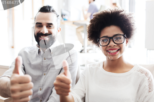 Image of happy creative team in office showing thumbs up