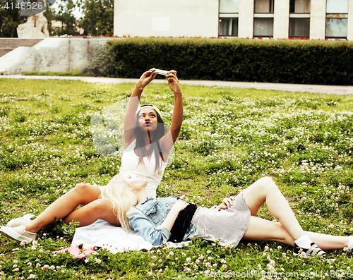 Image of two young pretty teenager girls best friends laying on grass making selfie photo having fun, lifestyle happy people concept, students at summer