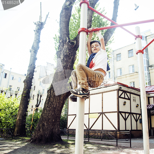 Image of little cute blond boy hanging on playground outside, alone training with fun, lifestyle children concept