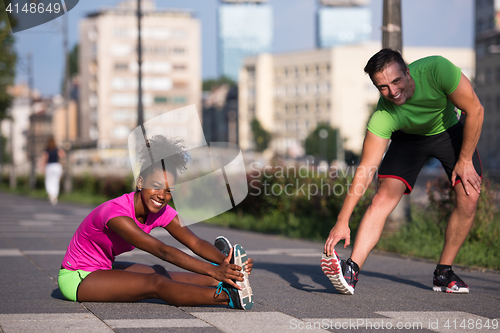 Image of jogging couple warming up and stretching in the city