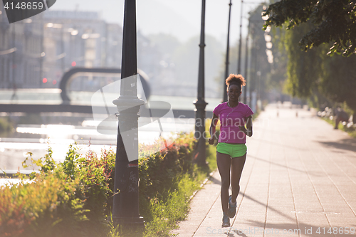 Image of african american woman jogging in the city