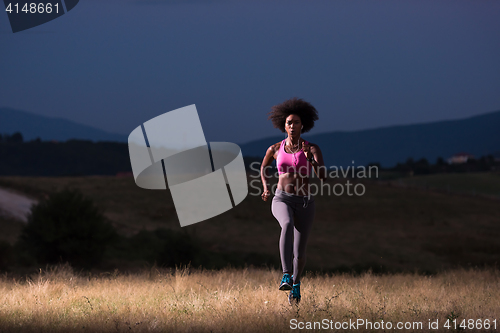 Image of Young African american woman jogging in nature