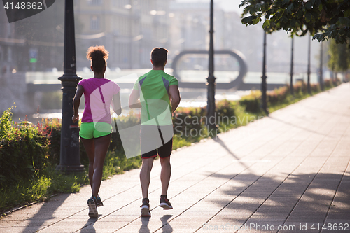 Image of young multiethnic couple jogging in the city