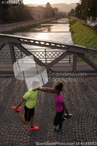 Image of jogging couple warming up and stretching in the city