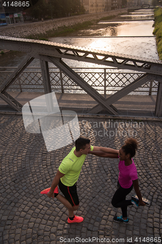 Image of jogging couple warming up and stretching in the city