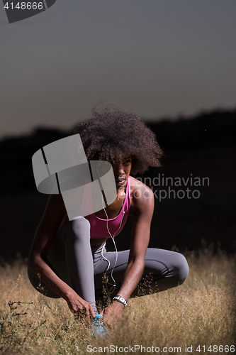 Image of black woman runner tightening shoe lace