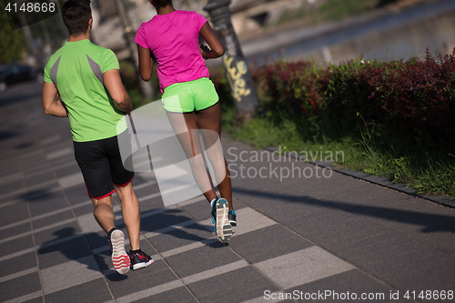 Image of young smiling multiethnic couple jogging in the city