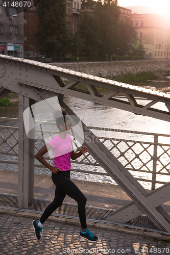 Image of african american woman running across the bridge