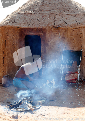 Image of Himba man adjusts wooden souvenirs